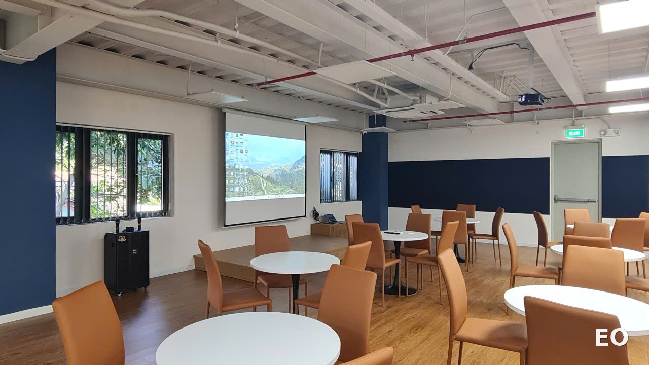 Khu vực đào tạo nội bộ với sân khấu gỗ thấp và màn chiếu tại Đông Đô Partners